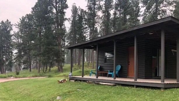 A cabin with a porch, a small table, and two chairs.