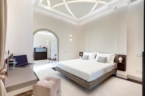 Quarto moderno com uma cama grande, uma escrivaninha com um laptop e uma divisória de vidro.