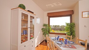 A dining area with a table set for four, a cabinet with glass doors, and a window with a view of the outdoors.