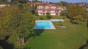 A residential area with a large swimming pool and a smaller pool, surrounded by lush greenery and multi-story buildings. - Petronella in Soiano (Soiano del Lago)