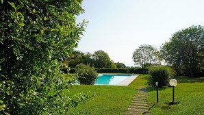 A swimming pool surrounded by lush greenery and a stone pathway.