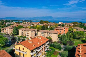 A residential area with multi-story buildings, balconies, and a view of a lake and mountains in the background.