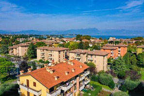A residential area with multi-story buildings, balconies, and a clear view of the sea and mountains in the background.