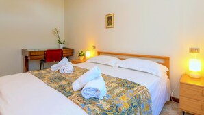 A hotel room with two beds, a desk, and a chair. There are towels on the beds and a potted plant on the desk. - Villaggio dei Fiori - Viola (Sirmione)