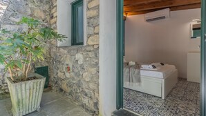 A stone-walled room with a bed, a potted plant, and a window. - Varenna Beach Perledo (Perledo)