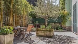 A patio with a table and chairs, surrounded by potted plants and a small tree. - Varenna Beach Perledo (Perledo)