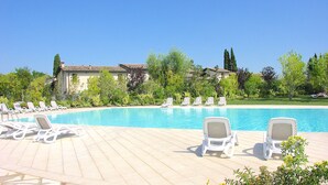 Un espace piscine doté de chaises longues et d’une piscine à l’eau d’un bleu cristallin.