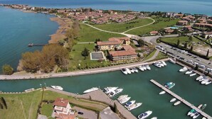 Vue aérienne d’une ville côtière avec un port de plaisance, des immeubles résidentiels et une montagne en arrière-plan.