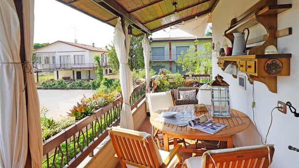 A covered outdoor seating area with a table, chairs, and a lantern. - Appartamento Balander (Sirmione)