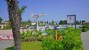 A marina with boats, a sign for 'Sirmione 2 Yacht Club', and a palm tree in the foreground. - Appartamento Balander (Sirmione)