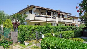 A two-story residential building with balconies, a garden, and a gate. - Appartamento Balander (Sirmione)