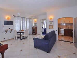 Relax in this open-plan living area with a sofa, dining table, and mounted TV, perfect for unwinding and enjoying quality time with loved ones.