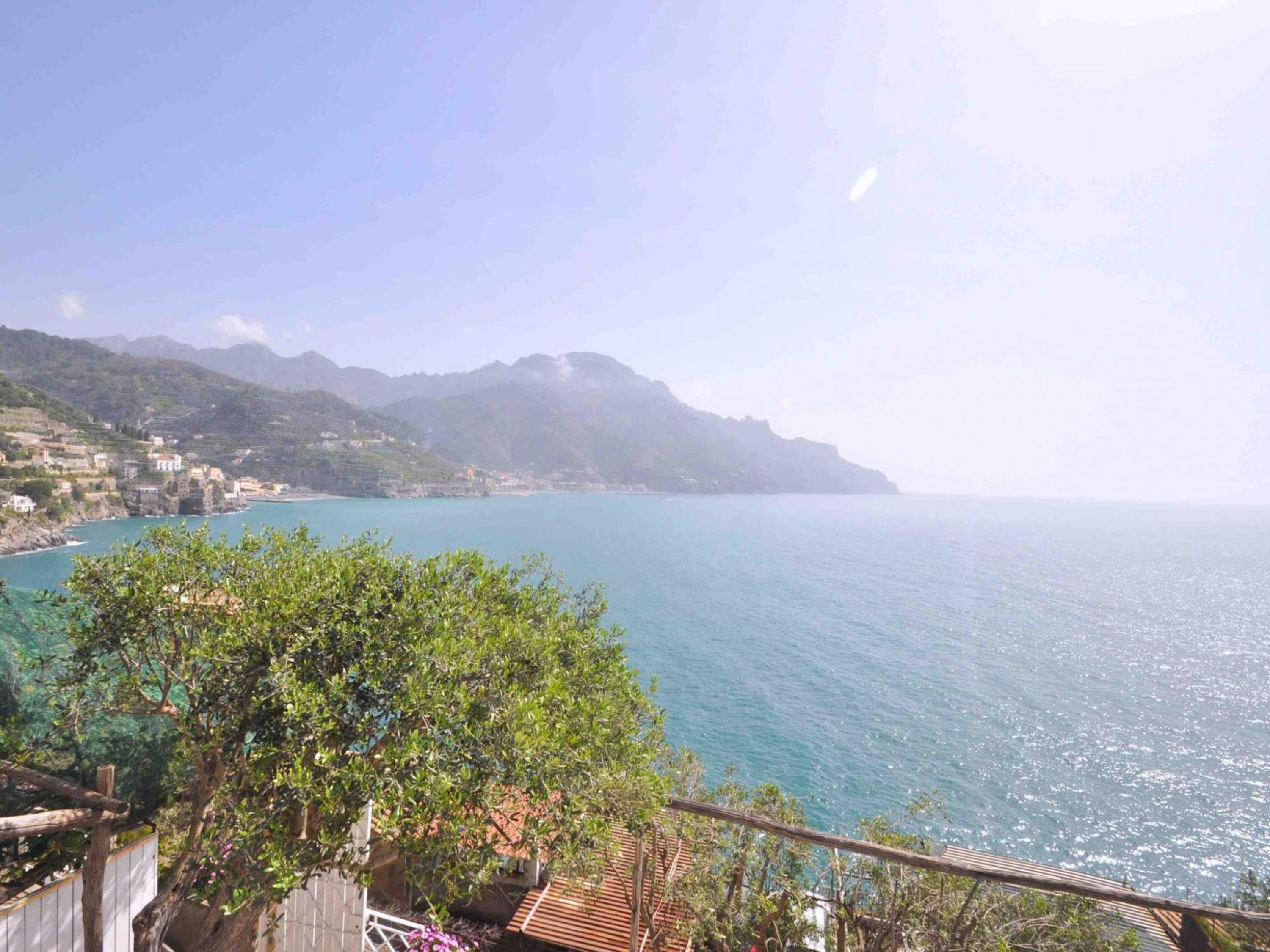 A coastal view with a clear sky, a calm sea, and a mountainous backdrop.