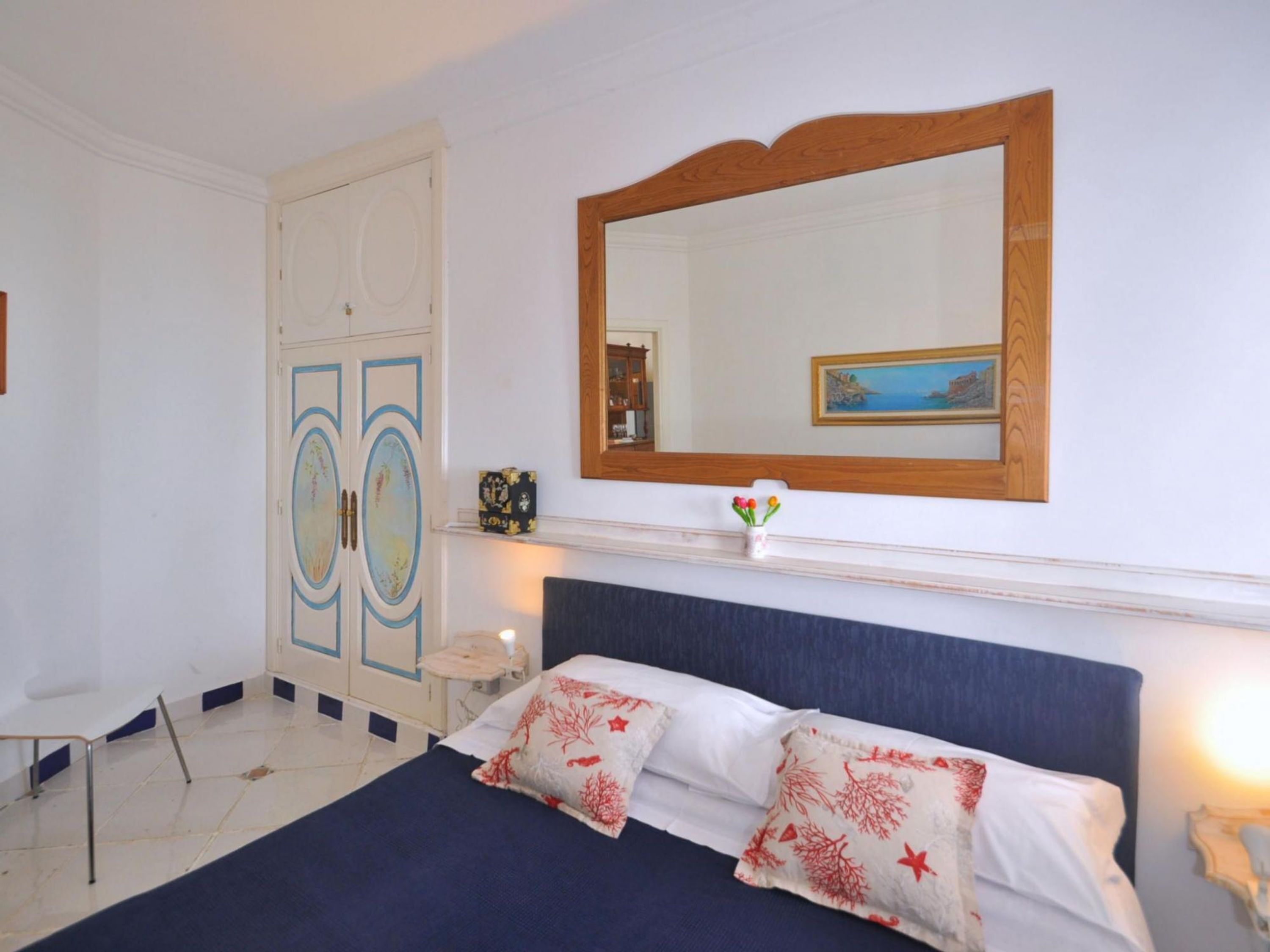 Une chambre à coucher avec un lit, une commode, un miroir et une table de chevet.