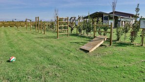 A grassy area with wooden climbing structures and a small wooden bridge.