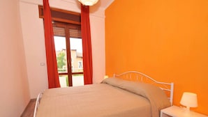 Ein Schlafzimmer mit Bett, Nachttisch, Lampe und einem fenster mit Vorhängen.