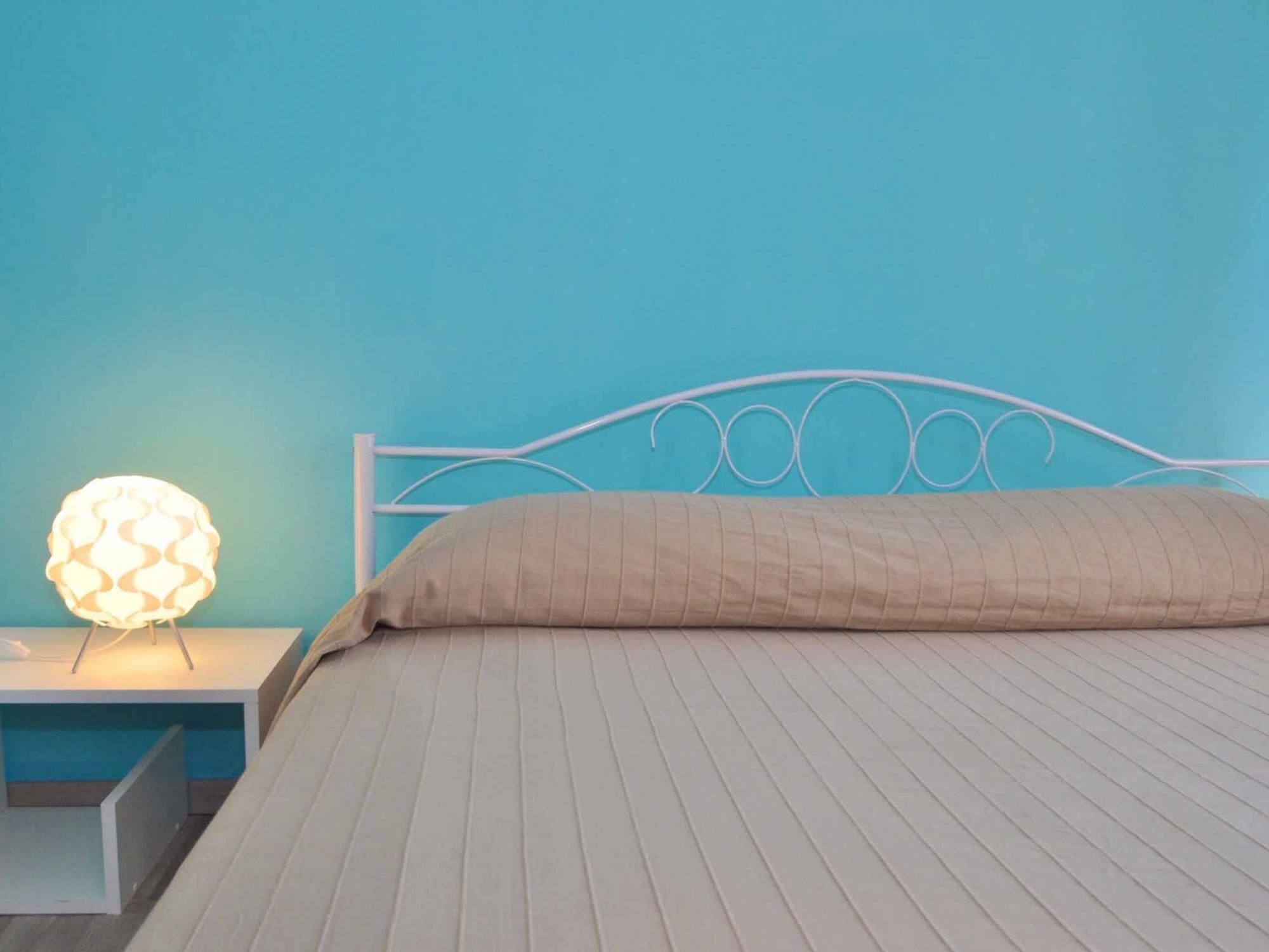 A bed with a white metal frame and a beige quilted bedspread.