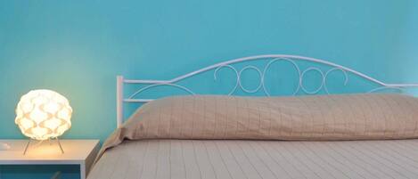 A bed with a white metal frame and a beige quilted bedspread.