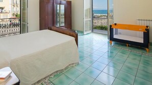A bedroom with a bed, a wardrobe, a small sofa, and a view of the sea through an open door. - Appartamento a Vietri sul Mare ID 3048 (Vietri sul Mare)