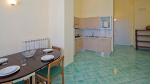 A dining area with a table set for four, a kitchen with a sink and cabinets, and a tiled floor. - Appartamento a Vietri sul Mare ID 3048 (Vietri sul Mare)