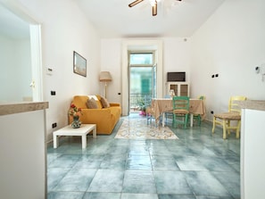 A living room with a sofa, a dining table with chairs, a small table with a vase, and a window with a view. - Appartamento a Vietri sul Mare ID 3050 (Vietri sul Mare)
