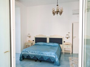 Ein Schlafzimmer mit einem Bett, zwei Nachttischen, einer Chandelüster und einer Tür.