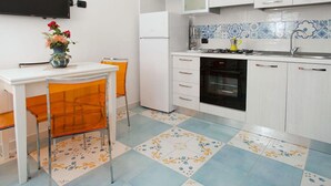A compact kitchen with white cabinets, a built-in oven, and a tiled backsplash. - Appartamento a Vietri sul Mare ID 3056 (Vietri sul Mare)