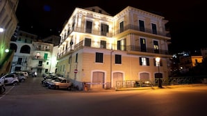 A multi-story building with balconies and a gated entrance, surrounded by parked cars and other buildings. - Appartamento a Vietri sul Mare ID 3056 (Vietri sul Mare)