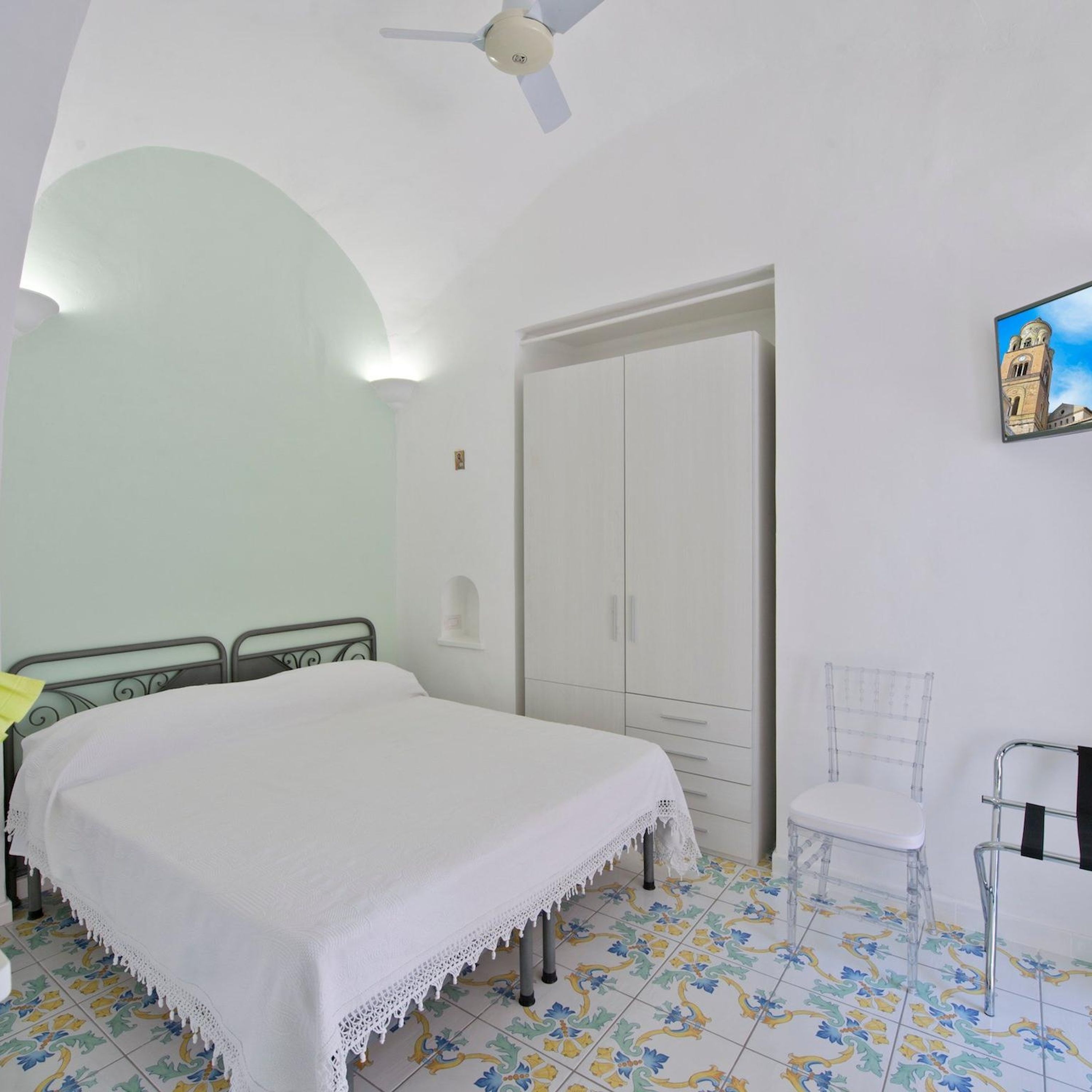 A bedroom with a bed, a wardrobe, a chair, and a ceiling fan.