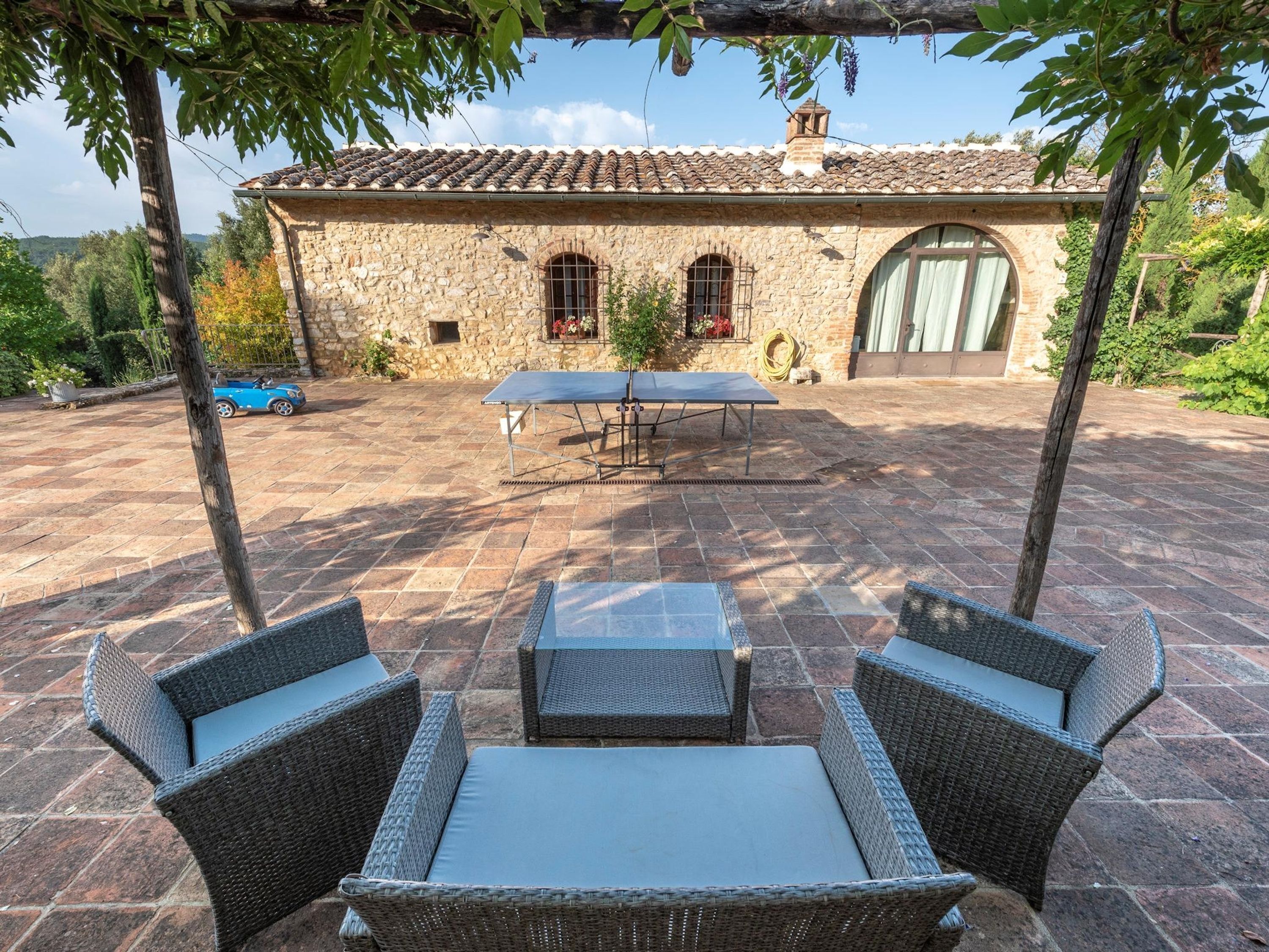 An outdoor patio with stone flooring, wicker furniture, and a ping pong table.