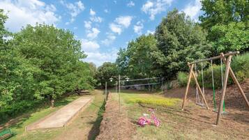 A playground with swings, a slide, and a tennis court.