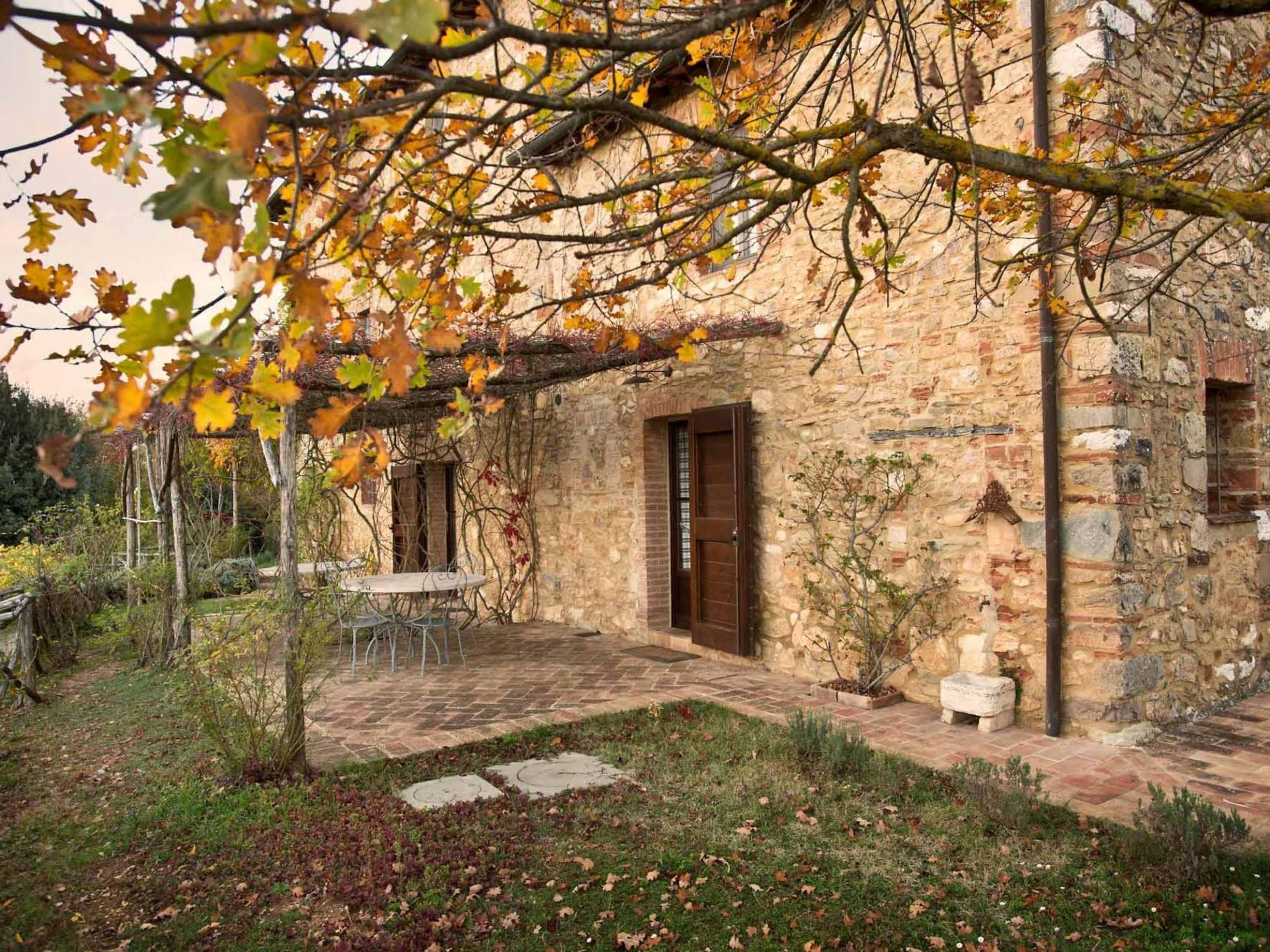 A rustic stone building with a covered patio area, a small table, and a door.