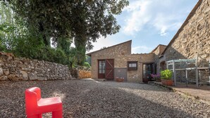 A stone building with a gravel courtyard, a red plastic chair, and potted plants. - Apartment in Chianti With Pool ID 453 (Casole d'Elsa)