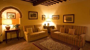 A cozy living room with a sofa, armchairs, a rug, and framed pictures on the walls. - Apartment in Chianti With Pool ID 453 (Casole d'Elsa)