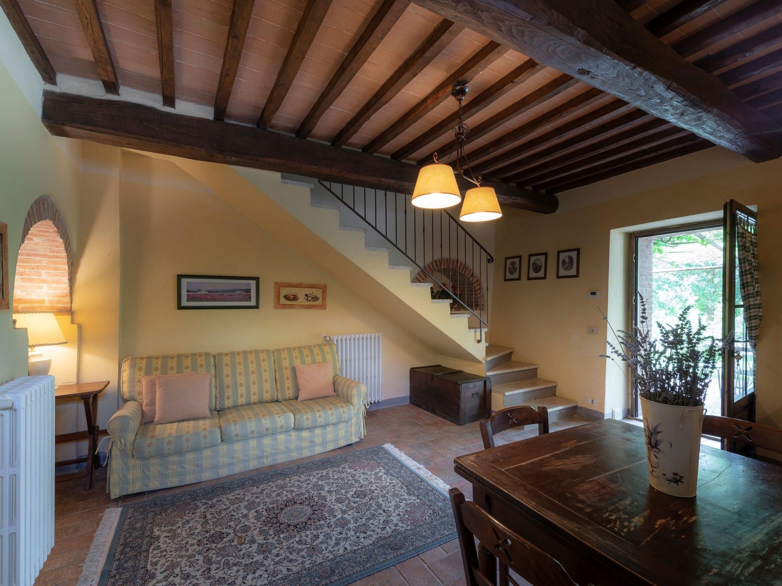 Una sala de estar acogedora con un sofá, una mesa de comedor y una escalera que sube a un nivel superior.