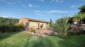A stone building with a tiled roof, a paved driveway, and a well-maintained garden with various plants and flowers. - Country House a Casole d Elsa ID 451 (Casole d'Elsa)
