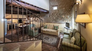 A rustic interior with a stone wall, a staircase, a sofa, and a television. - Apartment in Chianti With Pool ID 452 (Casole d'Elsa)