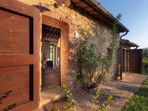 Traditional stone building with a wooden door and garden area, featuring a tiled floor and wooden archway.