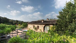 A rustic stone building with a tiled roof, surrounded by lush greenery and a clear sky. - Apartment in Chianti With Pool ID 455 (Casole d'Elsa)