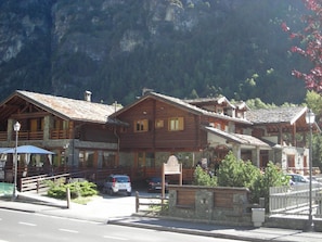 A traditional wooden chalet with a stone facade, a covered porch, and a mountain backdrop. - Apartment La Gran Becca - ID 831 (Antey-Saint-Andre)