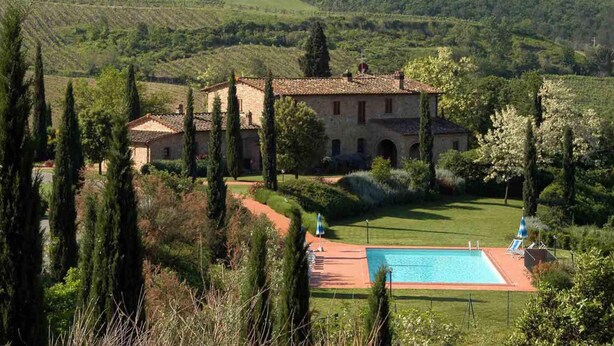 Une villa avec piscine, entourée de cyprès et d’un paysage luxuriant.