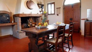 Une cuisine rustique avec une cheminée en briques, une table en bois et des chaises.
