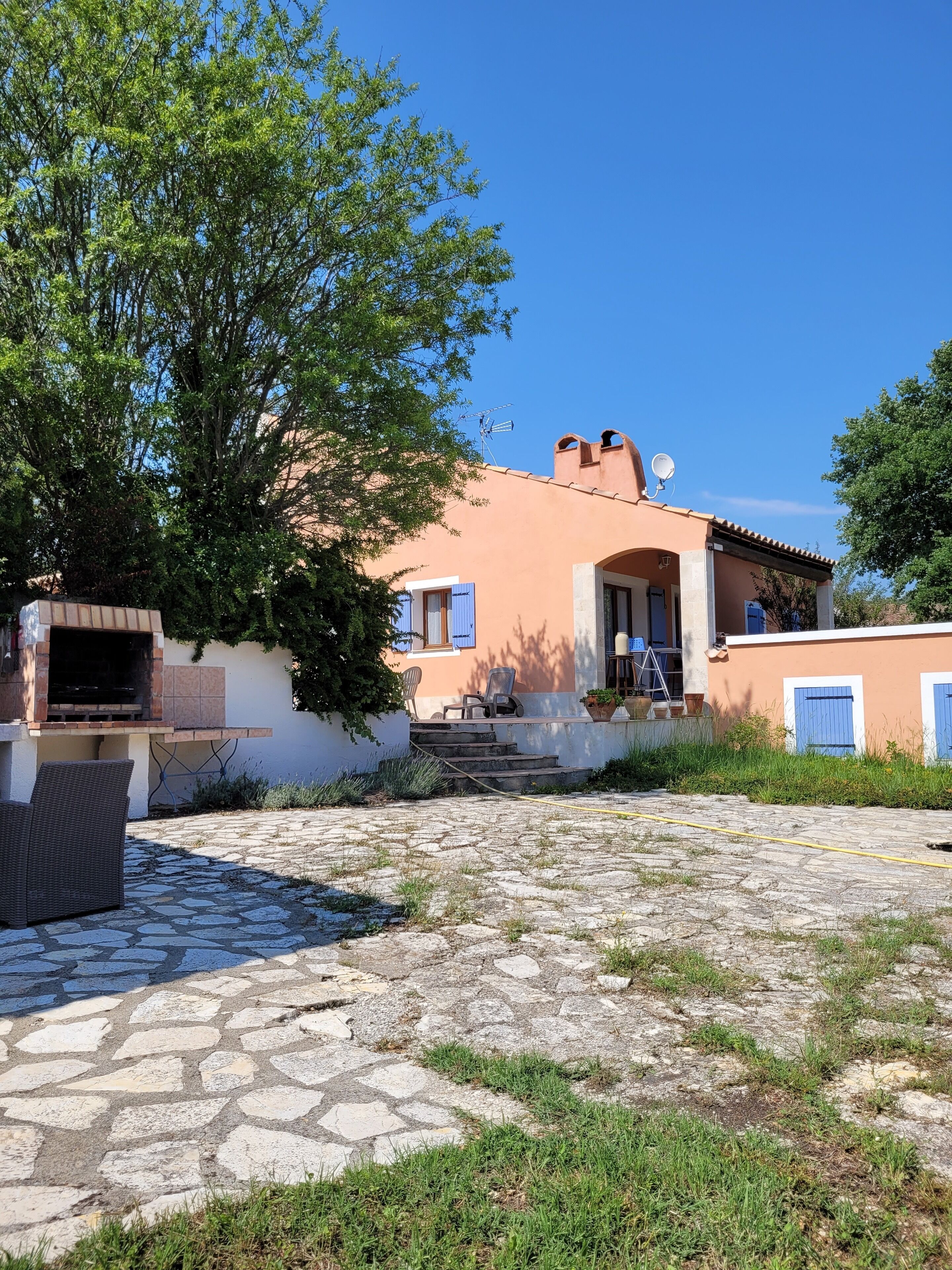 A house with a stone patio, outdoor seating, and a barbecue area.