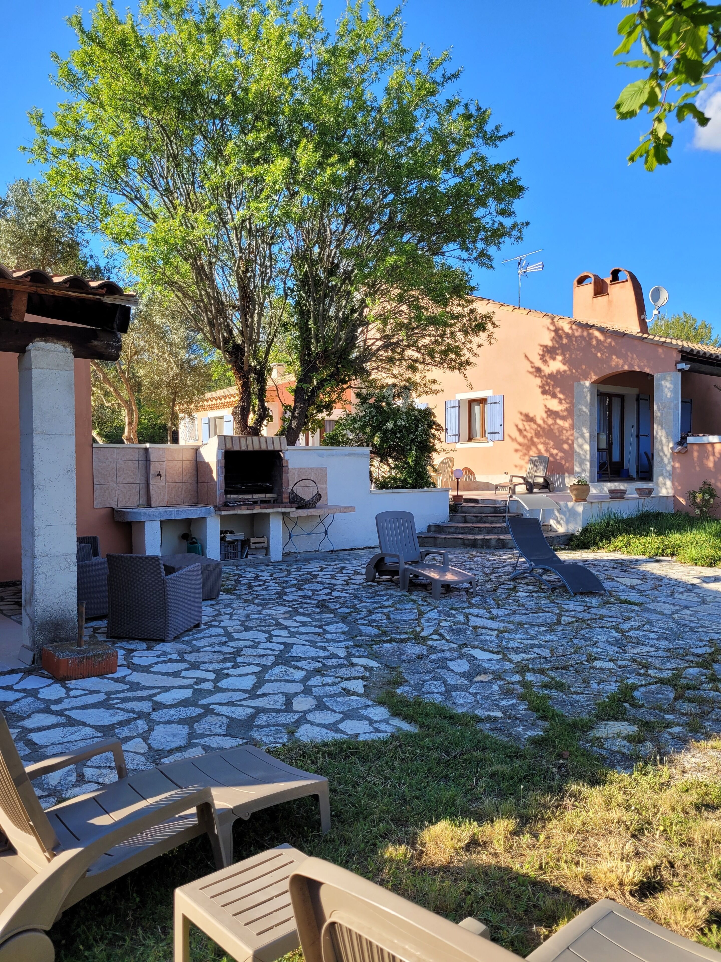 A courtyard with stone flooring, outdoor seating, and a barbecue area.