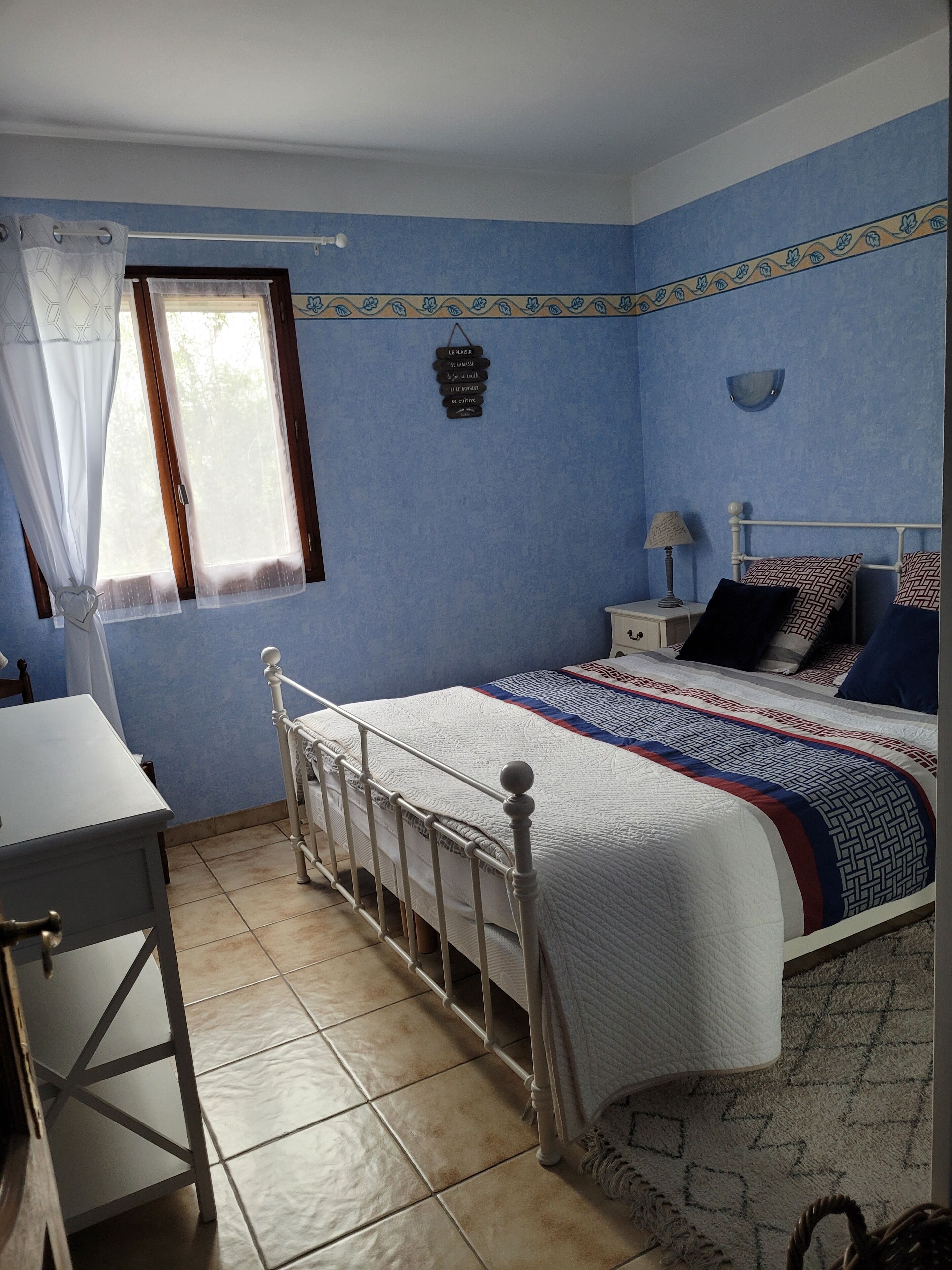 A bedroom with a bed, bedside table, and a window with curtains.