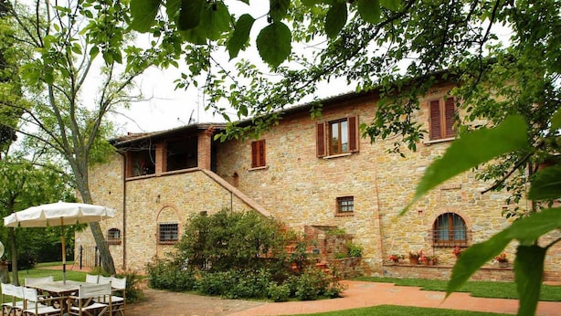 Ein Gebäude aus Stein mit Ziegelaußenwand, ein kleiner Garten mit Rasenfläche und Außenbereich mit Sonnenschirmen.
