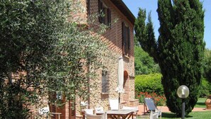 An outdoor patio area with brick flooring, wooden furniture, and a stone building in the background. - Country House in Chianti With Pool ID 33 (Montaione)