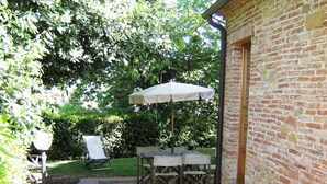 Un espace patio avec un mur en briques, une table avec un parasol et une chaise de jardin.