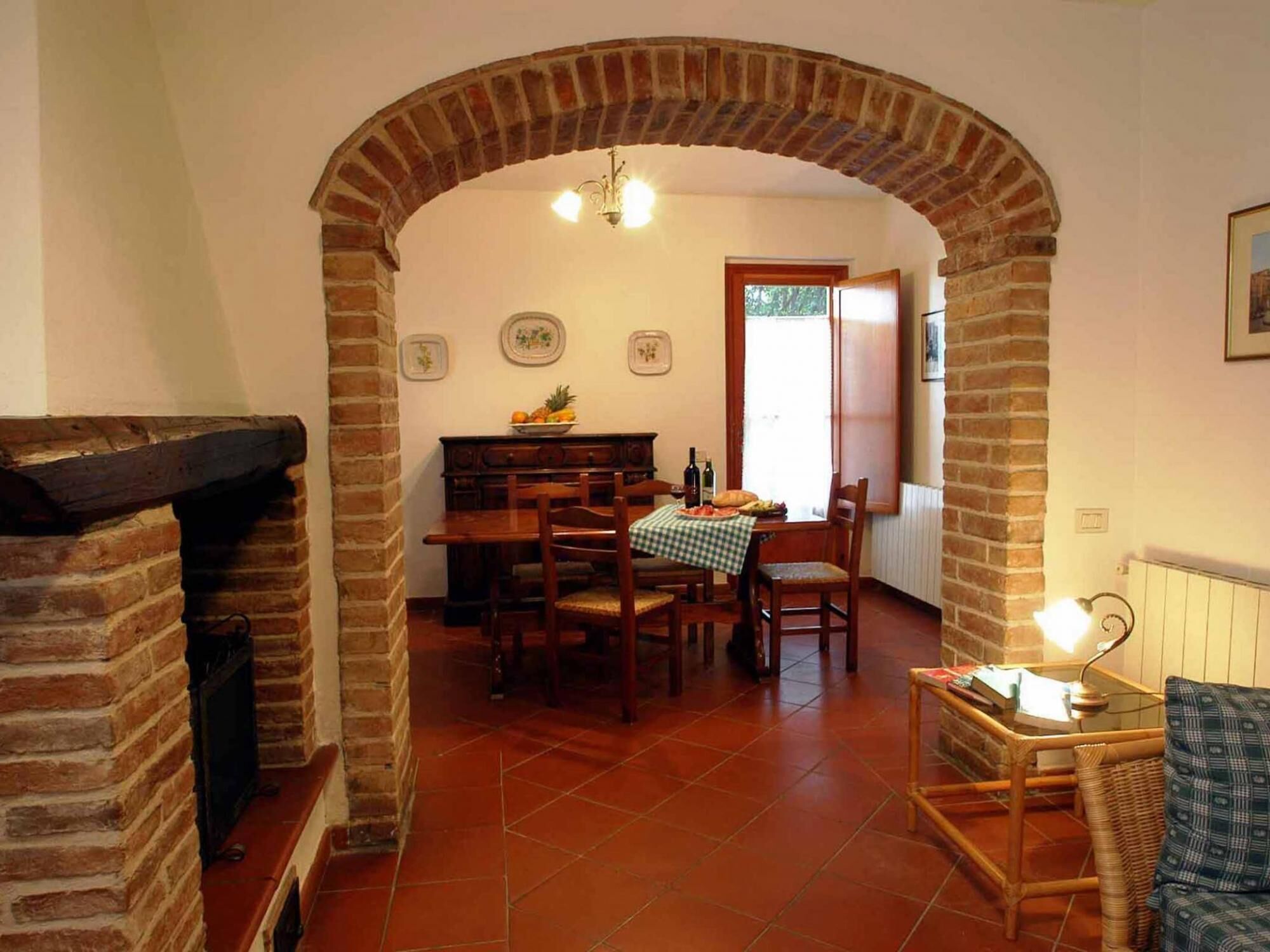 A dining area with a brick fireplace, a wooden table with chairs, and a window with a view.