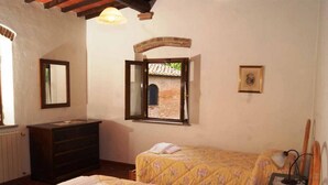 Un dormitorio con dos camas, un aparador, un espejo, una ventana con una persiana levantada y un cuadro en la pared.